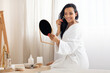 © Prostock-studio - Cheerful Woman Massaging Face With Stone Roller Sitting In Bathroom