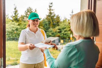 woman customer get a pen form delivery service woman in uniform for signature receiving parcel post box from courier at home, express delivery and shopping online concept