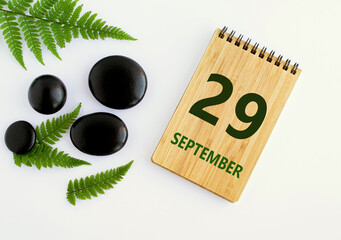September 29. 29th day of the month, calendar date. Notepad, black SPA stones, green leaves. Autumn month, day of the year concep