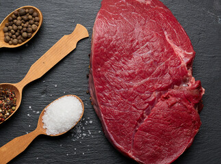 Wall Mural - Raw beef tenderloin lies on a wooden cutting board on a black table, top view