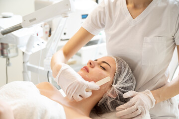 Wall Mural - Beautician applying hydro gel mask on the young woman face, before laser treatment in beauty salon.