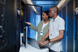 Waist up portrait of two IT engineers inspecting server cabinets and setting up internet network