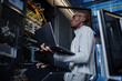 © Seventyfour - Side view portrait of black man working as IT engineer holding laptop while setting up internet network in server room