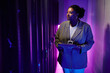 © Seventyfour - Portrait of female system administrator inspecting data network in server room lit by neon light, copy space