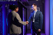 © Seventyfour - Waist up portrait of two business partners shaking hands while standing in data center interior