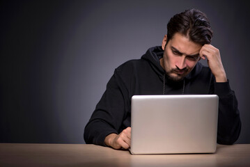 young male hacker on grey background