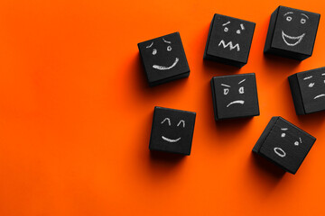 Many cubes with different emotions on orange background, flat lay and space for text. Emotional management