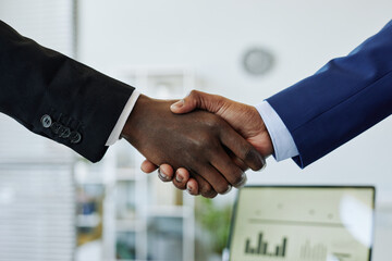 Close up of two business people shaking hands after successful partnership negotiation in office