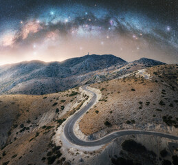 Wall Mural - milky way arch and winding mountain road at night. sky with arched milky way and bright stars in sum