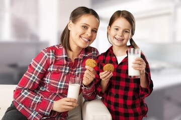 Wall Mural - Happy Family Mother And Daughter Holding Glasses While Sitting Together In Kitchen, Enjoying Healthy Drink