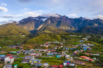 Wall Mural - Beautiful aerial view of rocky mountain range Mount Kinabalu with village and green vegetation at foreground.