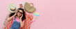 Young female African-American tourist with beach accessories on pink background with space for text, top view