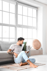 Handsome barefoot man reading newspaper at home