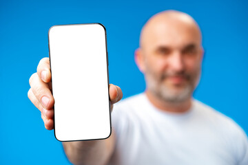 Middle-aged man showing blank smartphone screen with copy space against blue background
