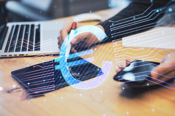 Fototapete - businessman hands using digital tablet and smartphone on desktop with laptop and glowing euro hologram on blurry background. E-commerce, online banking, cryptocurrency and finance concept. 