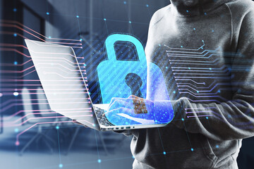 Poster - Hacker in hoodie using laptop with glowing padlock hologram and lines on blurry office interior background. Secure, hacking, safety and protection concept. Double exposure.