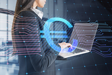 Aufkleber - Young businesswoman using laptop with glowing euro hologram and lines on blurry office interior background. E-commerce, online banking, cryptocurrency and finance concept. Double exposure.
