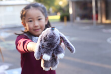 Young School Girl Holding Out Her Toy Bunny To The Camera