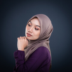 Close up portrait of a beautiful female model wearing traditional dress and hijab, a lifestyle apparel for Muslim women isolated on grey background. Idul Fitri and hijab fashion concept.