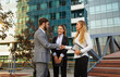 © NDABCREATIVITY - Group of business man and woman team at office shaking hands outdoors