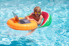 Business And Summer. Kid Remote Working On Laptop In Pool. Little Business Man Working Online On Laptop In Summer Swimming Pool Water.