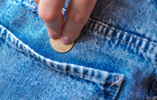 Hand Puts Gold Coin Change In Jeans Pocket .Savings Concept 