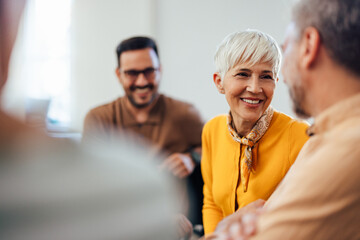 Wall Mural - Portrait of a smiling mature woman, looking at one man, talking.