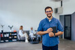 © bnenin - Close up of a man, standing at the office, smiling for the camera while holding a tablet.