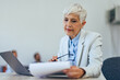 © bnenin - Close up of a mature businesswoman, holding notes and checking them.
