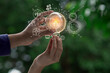 Hand holding light bulb and sustainable development interface icons on green background, Technology and environment concept.	