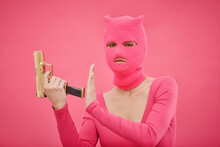 Portrait Of Criminal Girl In Pink Balaclava Holding Gun And Looking At Camera, She Ready For Fight