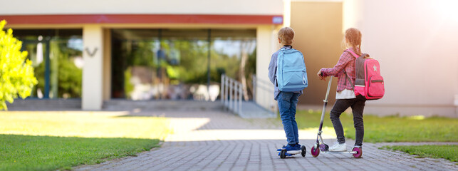 Wall Mural - Girl and boy riding by scooters in school to study at it.