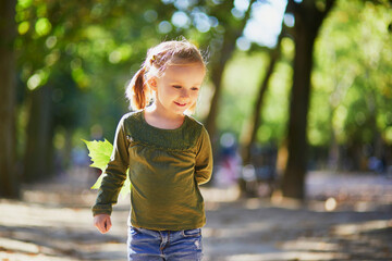 Wall Mural - Adorable preschooler girl enjoying nice and sunny autumn day outdoors