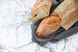 © Sergey - Artisan baked french sourdough baguette on kitchen towel on marble table, top view. Free space for text