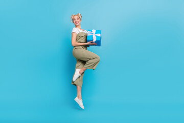 Sticker - Full body photo of sweet young blond lady jump with present wear t-shirt overall shoes isolated on blue background