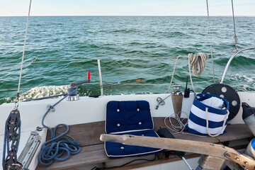 Wall Mural - White yacht sailing at sunset. Boat side railing, winch, rigging equipment. View from the cockpit. Baltic sea. Transportation, leisure activity, cruise, sport, racing, yachting, summer vacations