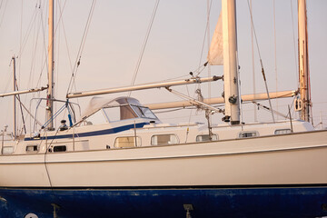 Wall Mural - White two masted cruising sailboat standing on land in a yacht club. Service, repair, winterization, transportation, sport, recreation, leisure activity