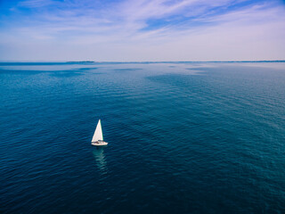 Wall Mural - Yacht sailing on opened sea. Aerial view of sailing boat on sea surface.