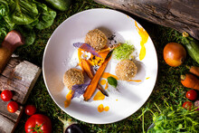 Breaded Balls, Boiled Carrots, Orange Sauce, Nasturtium Leaves, Flower Petals, And A Lacy Chip