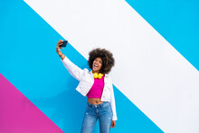 Young Woman Taking Selfie In Front Of Colorful Wall