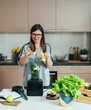 © Tijana - Smiling Woman Making Green Smoothie For Breakfast At Home