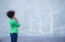 Young Woman Looking At Painted Wind Turbines On Wall