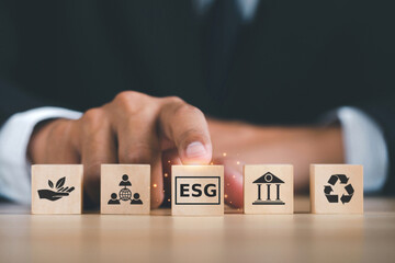 Wall Mural - ESG concept of environmental, social, and governance. Sustainable corporation development.Businessman Hand pushing wooden cubes abbreviation ESG standing in front of other ESG icons.