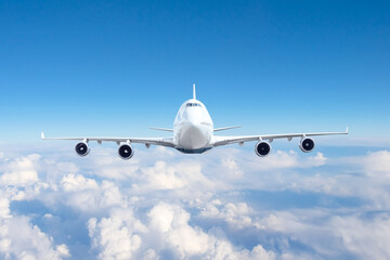 Wall Mural - Airplane travel flying in the sky, looking directly at the liner with four engines.