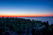 Gwiazdobloki chroniące falochron nadmorski. Zachód słońca przy umocnieniach brzegu morskiego