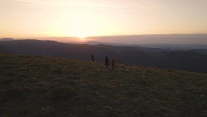 Wall Mural - Flying over group of excited hikers watching the sunset at the top of the mountain