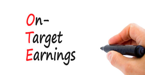 OTE on-target earnings symbol. Concept words OTE on-target earnings on white paper on a beautiful white background. Businessman hand. Business and OTE on-target earnings concept. Copy space.