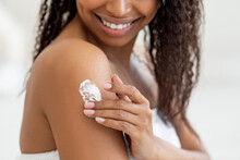 Closeup Shot Of Young Black Female Rubbing Moisturising Lotion To Skin