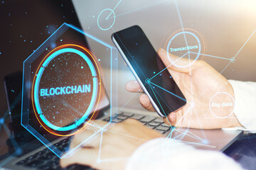 Aufkleber - Close up of hands using laptop keyboard and smartphone on desktop with creative polygonal blockchain hologram and blurry outdoor background. Technology and fintech concept. Double exposure.