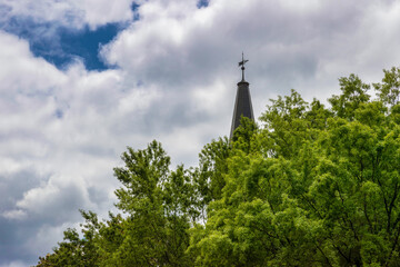 Steeple rises above tree tops into a cloudy sky